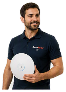 Bearded man in a navy polo shirt holding a round white wireless device with a blue ring and a 'U' button, wearing a DotaRoad logo polo.